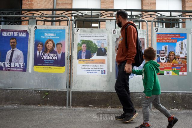 A man and a child walk past electoral posters in Toulouse
