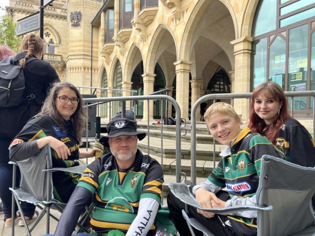 Kerry with her family, all wearing Saints shirts, sit on chairs outside the Guildhall in Northampton