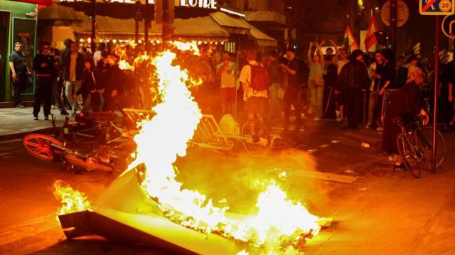 A barricade on fire in front of a group of protesters