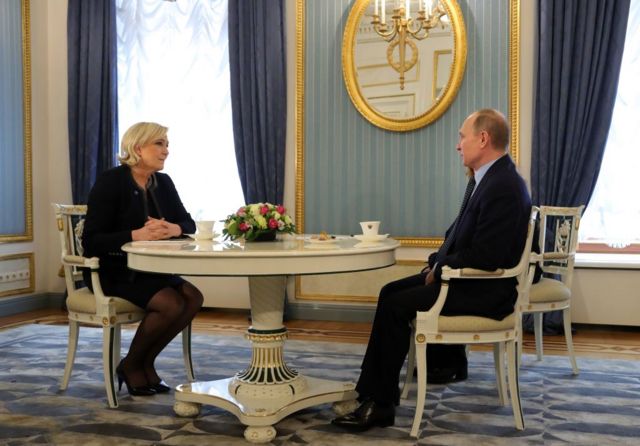 Marine Le Pen and Vladimir Putin sat around a table