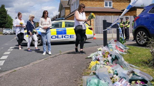 People leave flowers near the police crime scene in Bushey