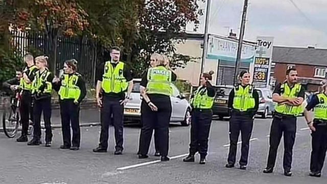 Police officers form a line across a street in Harehills