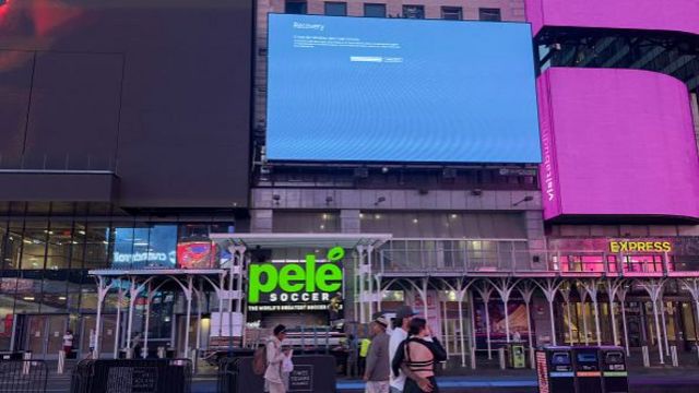 A billboard above a line of shops showing the "blue screen of death".