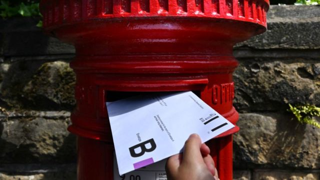 An envelope containing a Postal Vote for the upcoming UK General Election is posted