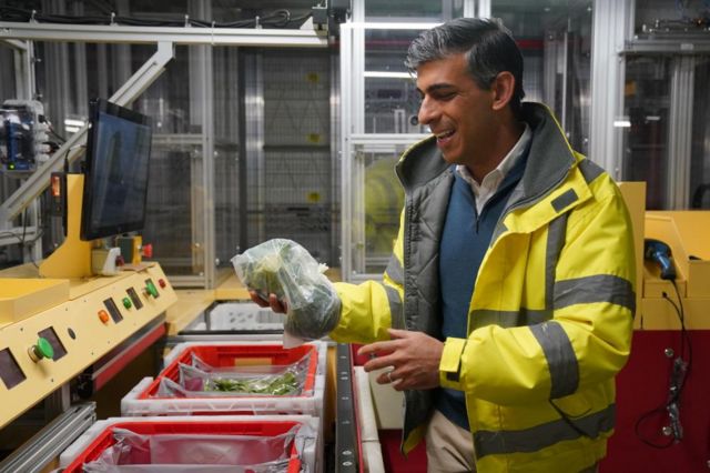 Prime Minister Rishi Sunak holds a broccoli during a visit to an Ocado distribution centre.