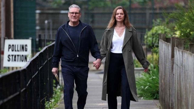 Keir Starmer walking, casually dressed / wearing casual clothes, with wife Victoria, at a polling station