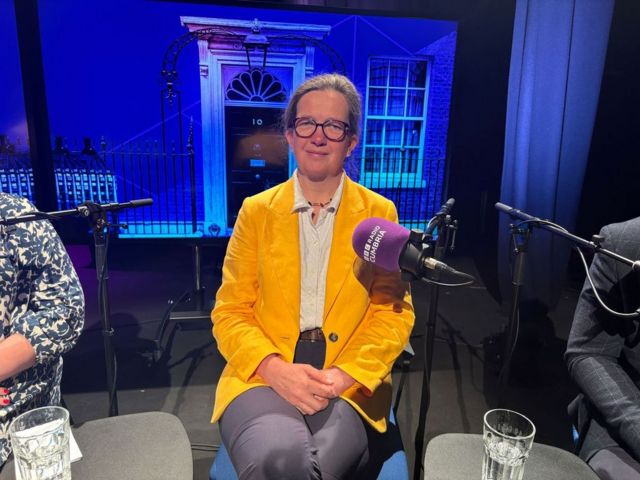Liberal Democrat candidate Julia Aglionby wears a yellow jacket and sits in the BBC Cumbria election debate studio