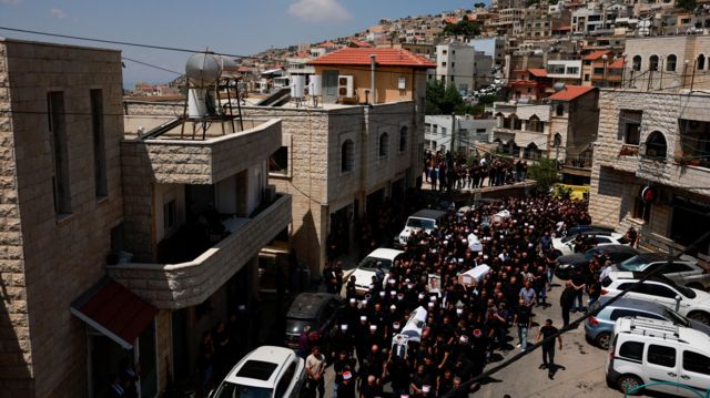 Mourners carry coffins during the funeral of children who were killed at a soccer pitch by a rocket Israel says was fired from Lebanon, in Majdal Shams