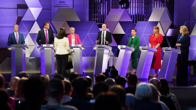 Party representatives stand on stage at a BBC election debate