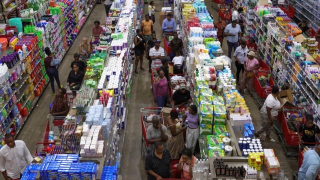 People wait in line with groceries ahead of the arrival of Hurricane Beryl in Kingston, Jamaica, on Monday