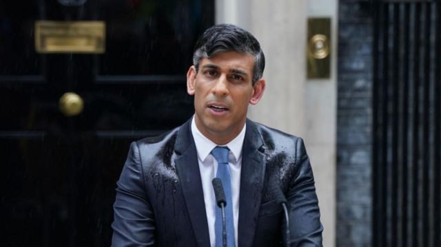 Prime Minister Rishi Sunak during a rain-soaked speech in Downing Street. The shoulder's of his suit are visibly wet.