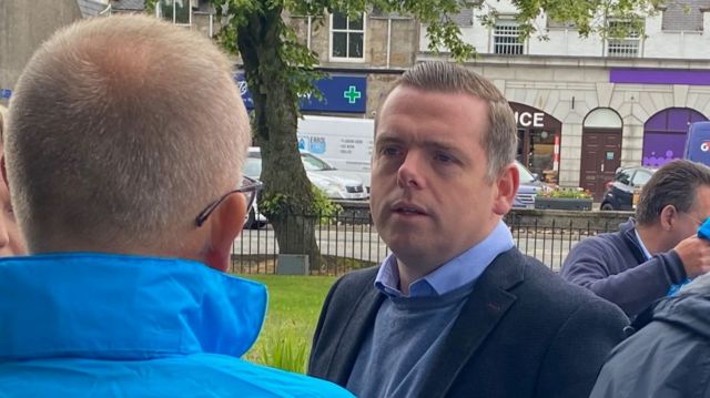Douglas Ross out campaigning wearing a suit