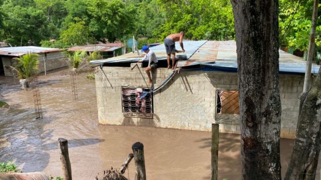 Residents fix the roof of their flooded house after a river swelled due to heavy rains following the passage of Hurricane Beryl on the road from Cumana to Cumanacoa, Sucre State, Venezuela, on July 2, 2024.