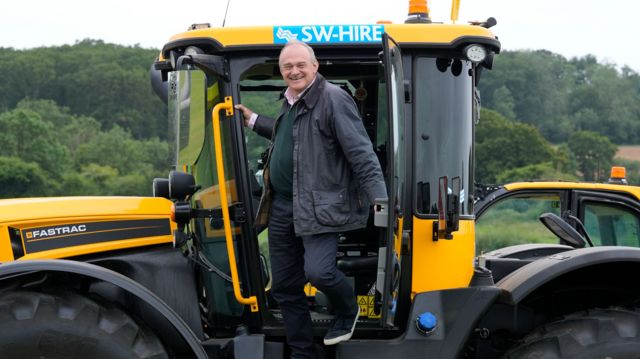 Sir Ed Davey climbs out of a JCB Fastrac after driving it during a visit to Owl Lodge in Lacock, 3 July 2024