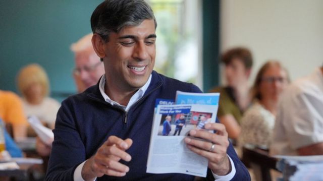 Prime Minister Rishi Sunak holds the Conservative Party's leaflets as he visits the Southern Parishes Conservative Club, while on the General Election campaign trail.