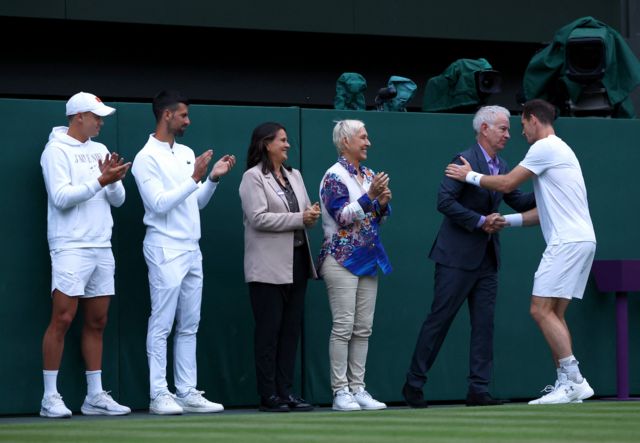 Holger Rune, Novak Djokovic, Conchita Martinez, Martina Navratilova and John McEnroe embrace Andy Murray