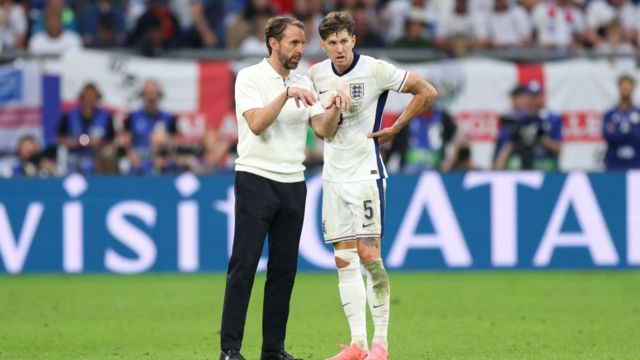 Gareth Southgate, Head Coach of England, speaks with John Stones of England ahead of the second half of extra time during the UEFA EURO 2024 round of 16 match between England and Slovakia at Arena AufSchalke on June 30, 2024 in Gelsenkirchen, Germany