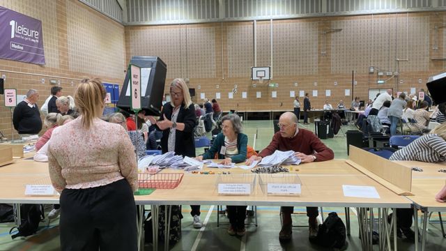 Votes being poured on to a table in a sport hall