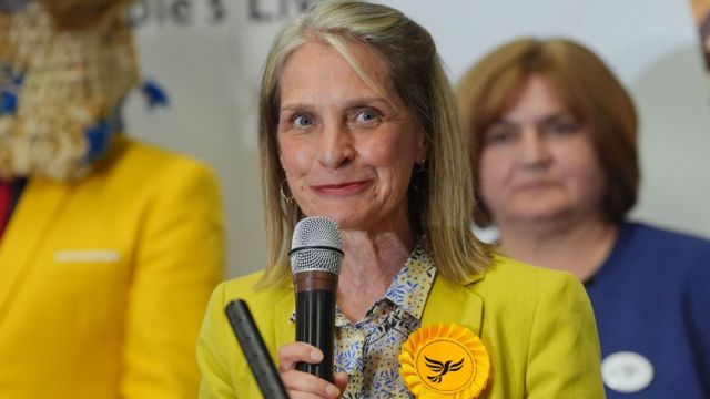 Wera Hobhouse in yellow speaking into a microphone