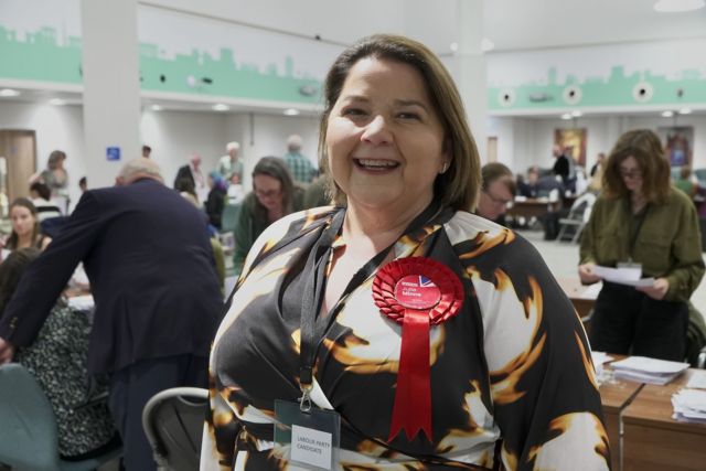 Labour's Carlisle candidate Julie Minns wearing a patterned dress and a red rosette