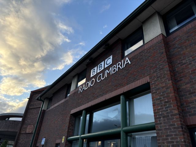 BBC Cumbria building, a redbrick building with a yellow cloud and blue sky beyond
