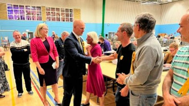 Liberal Democrat Max Wilkinson, wearing dark suit, and shaking hands with people at the count.