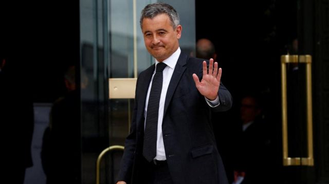 Darmanin waves as he exits a building
