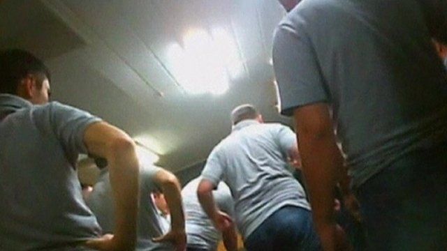 Still of footage of prison staff apparently abusing prisoners