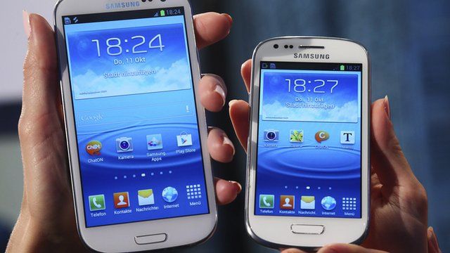 models hold a Samsung Galaxy S and a Galaxy S3 Mini (R) smartphones