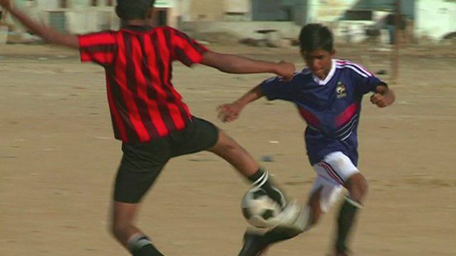 Two street children in Pakistan fight for possession of the ball