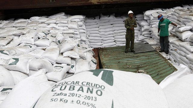 Workers stand on top of bags labelled "Cuban raw sugar" inside a North Korean flagged ship