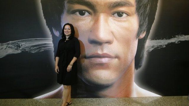 Shannon Lee, daughter of the late Kung Fu star Bruce Lee, poses in front of a promotional poster for Lee"s memorial exhibition