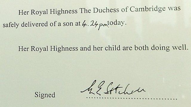 Baby news displayed on ornate easel outside Buckingham Palace