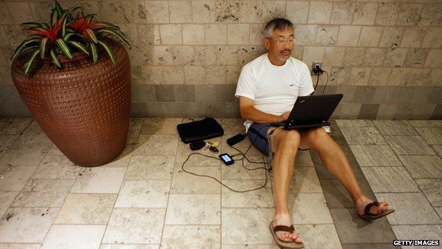 Man on laptop plugged in to wall socket