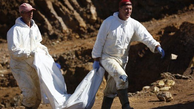 Two men carrying a bag of human remains
