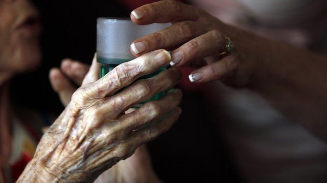 Nurse gives elderly woman a drink