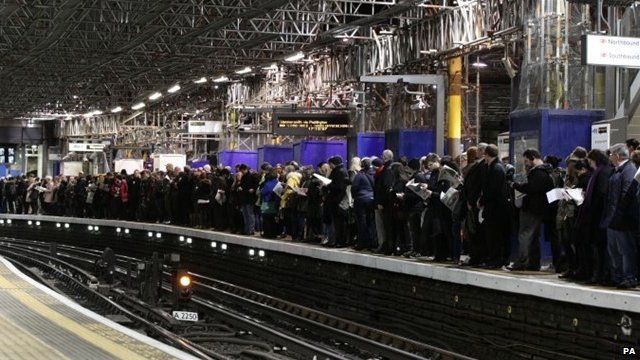 Commuters waiting for a train on a platform at Farringdon Underground station