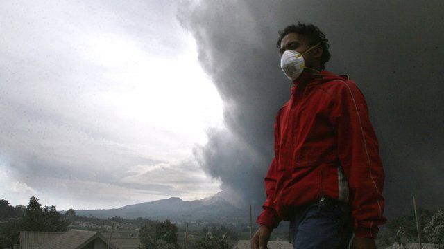 A resident of the Malang district in East Java evacuates as hot ash clouds erupt from Mount Kelud