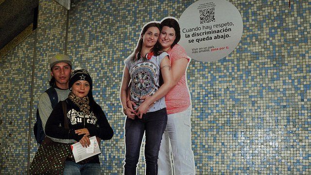 A couple pose in front of an advert promoting respect on the Santiago metro