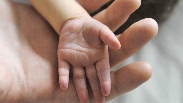 A person holds a baby's hand