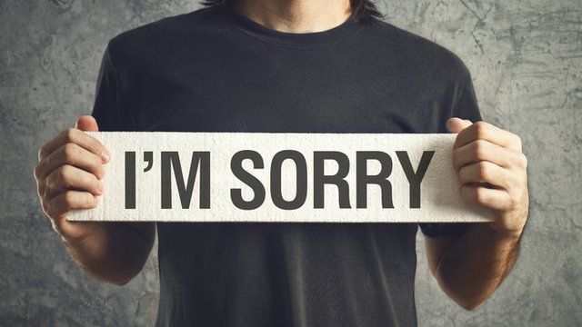Man holding "I'm sorry" sign