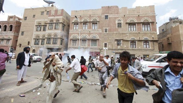 Followers of the Shiite Houthi movement flee from tear gas used by the riot police to disperse them, in Sanaa