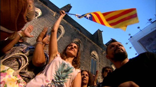 Protesters fly a Catalan flag