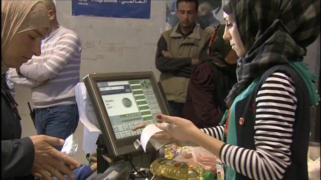 A shopper and cashier at a supermarket in Syrian refugee camp