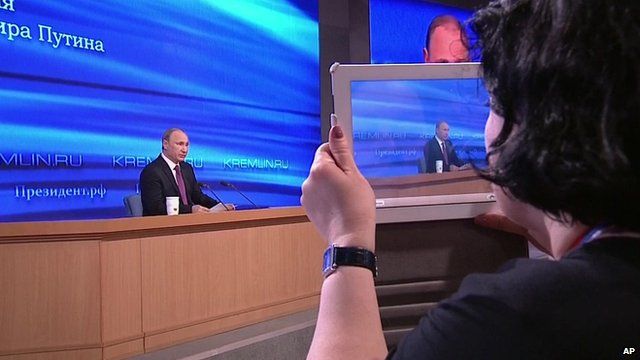 Woman using tablet to photograph Russian president Vladimir Putin during his end-of-year news conference