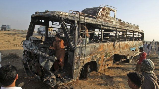 Pakistani gather around and inside the wreckage of a passenger bus