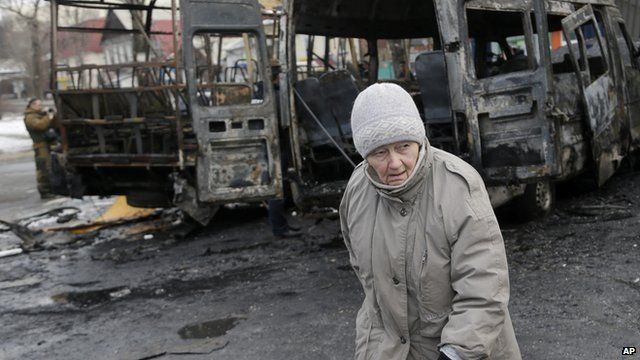 An elderly woman walks past vehicles destroyed in shelling between Russian-backed separatists and the Ukrainian government forces in Donetsk on 11 February 2015