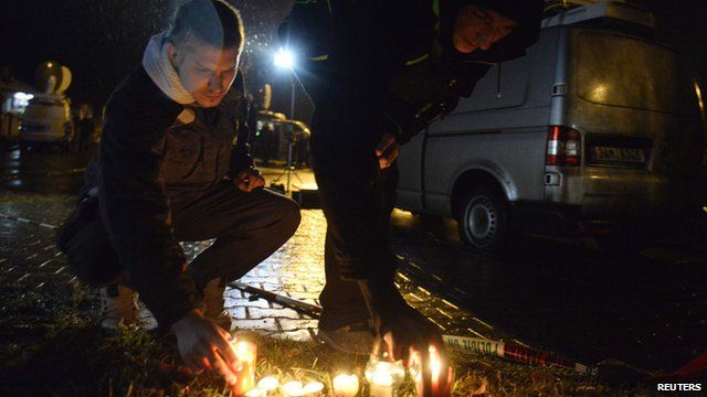 People light a candle near a restaurant where a gunman opened fire in Uhersky Brod, February 24, 2015