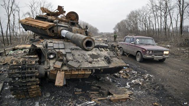 A car passes a destroyed tank abandoned on the road at a former Ukrainian army checkpoint outside the city of Chornukhyne in Ukraine on 2 March
