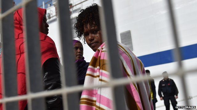 A migrant woman looks through a fence as she prepares to board a ship on 20 February, 2015 in Lampedusa, Italy